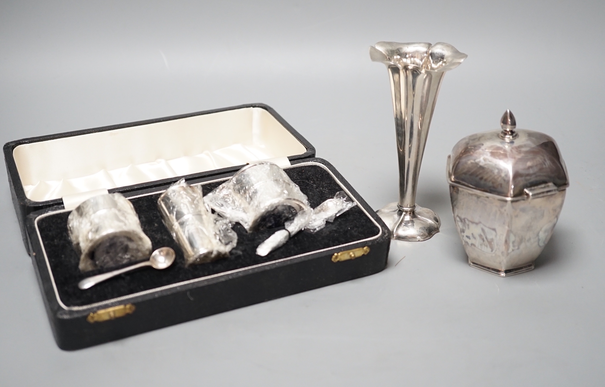 A George V silver hexagonal tea caddy, Sheffield, 1919, 10.5cm, a silver posy vase and a cased three piece silver condiment set.